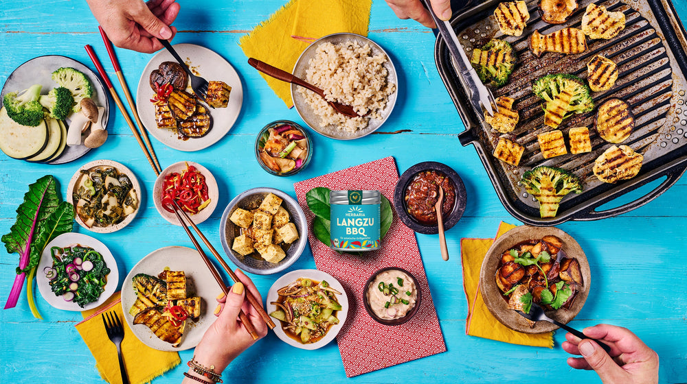 Korean BBQ Grill mit gegrilltem Gemüse, Reis, Tofu und Gewürzen auf blauem Tisch