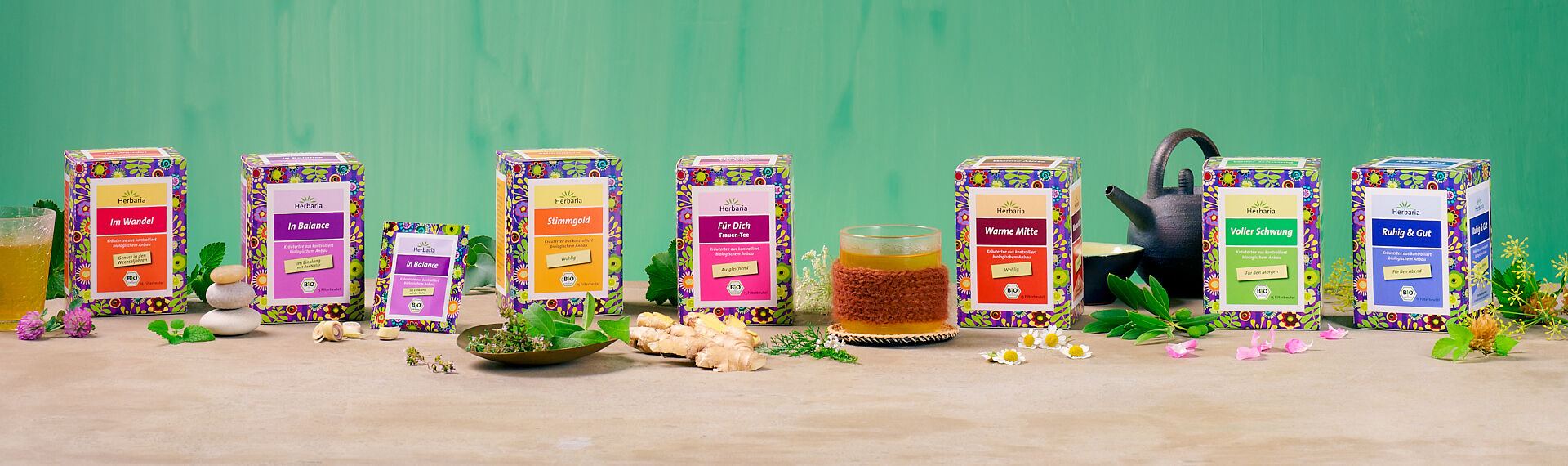 Bio Rose Minze Tee neben Teeglas, Teekanne und frischen Rosen auf hellem Hintergrund